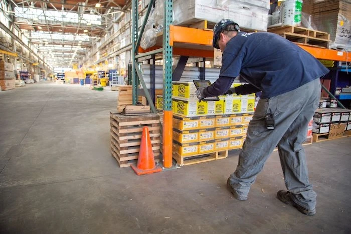 A man is checking parts/inventory in a large warehouse-type building.