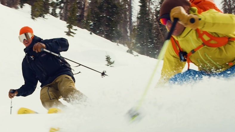 Low-angle action shot of two downhill skiers in deep powder.