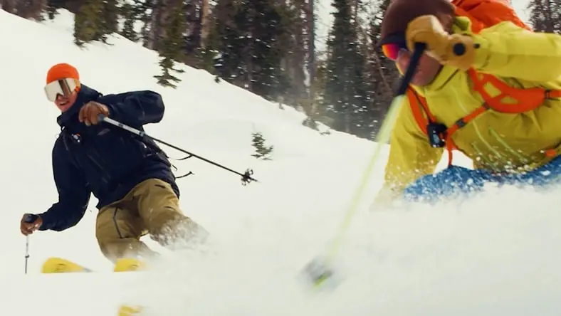 Low-angle action shot of two downhill skiers in deep powder.