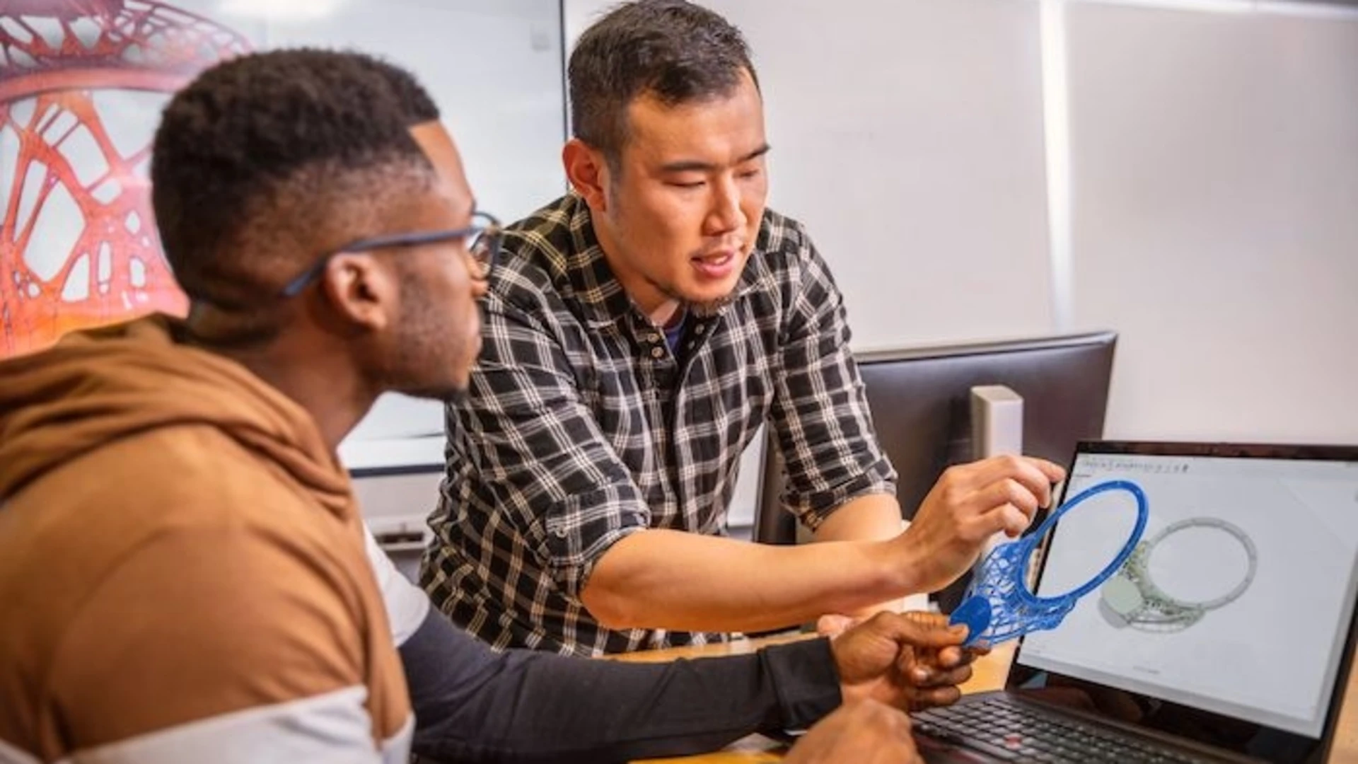 two people examining a generatively designed part in front of a laptop using software