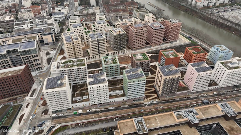 Aerial view of some of the buildings of the Paris Athletes’ Village showing solar panels and green spaces on their roofs.