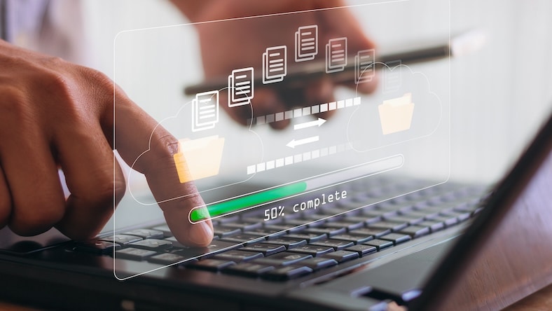 A hand using a laptop computer is overlaid with a loading bar icon on a virtual screen.