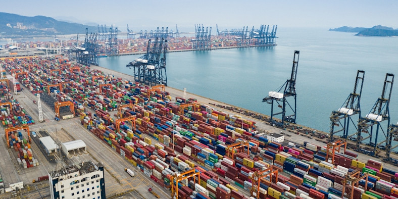 Aerial picture of a port with cranes and containers.