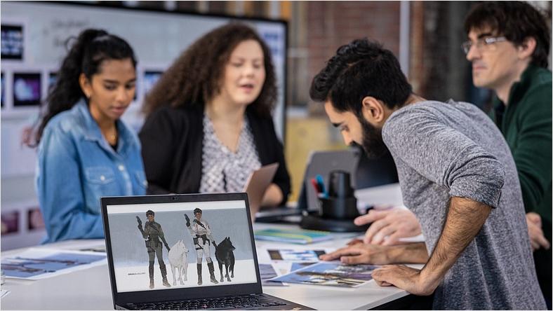 Several people stand around a table discussing content plans in a digital content creation studio.