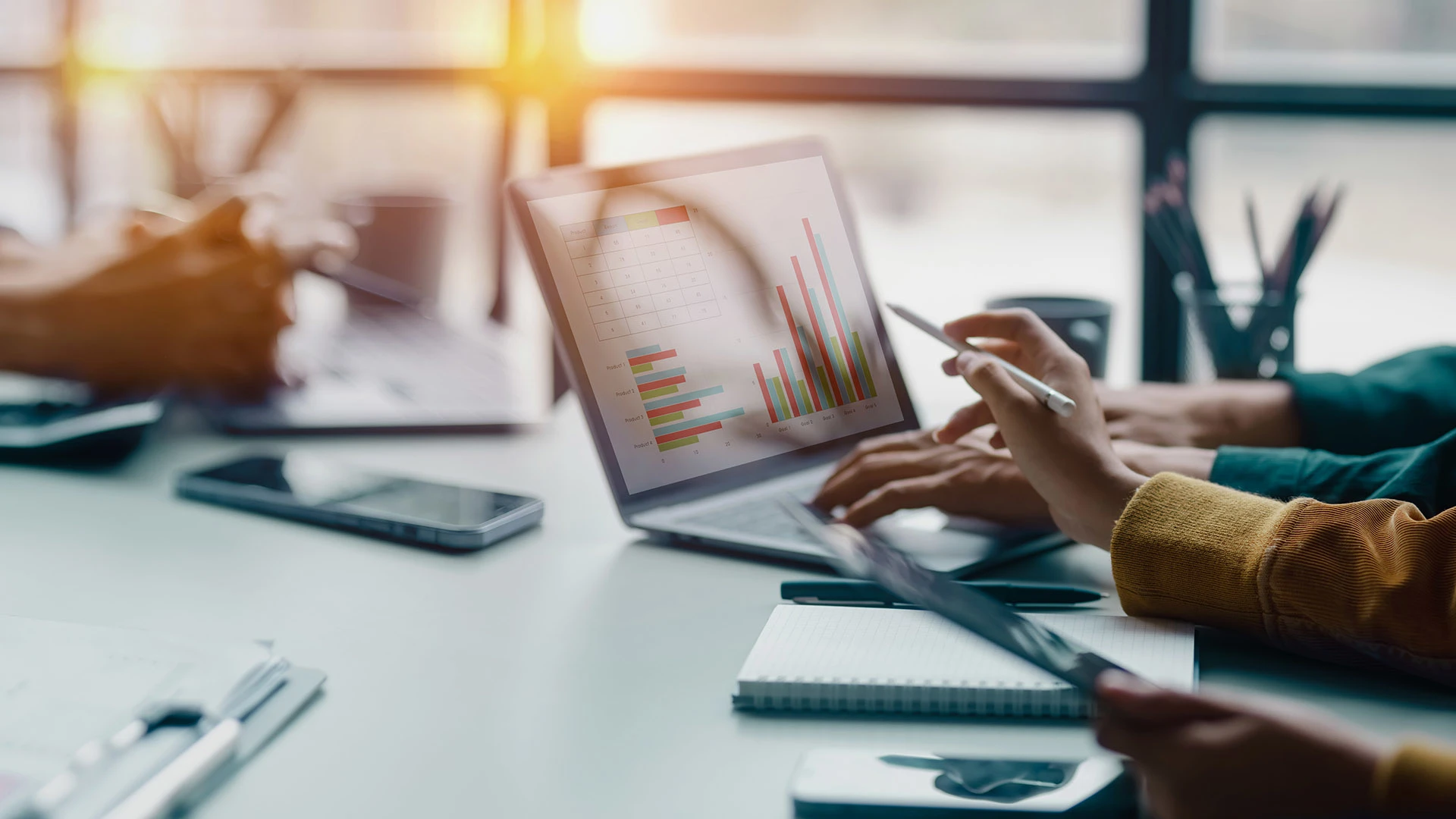 People at a meeting consult financial graphs on a laptop. 