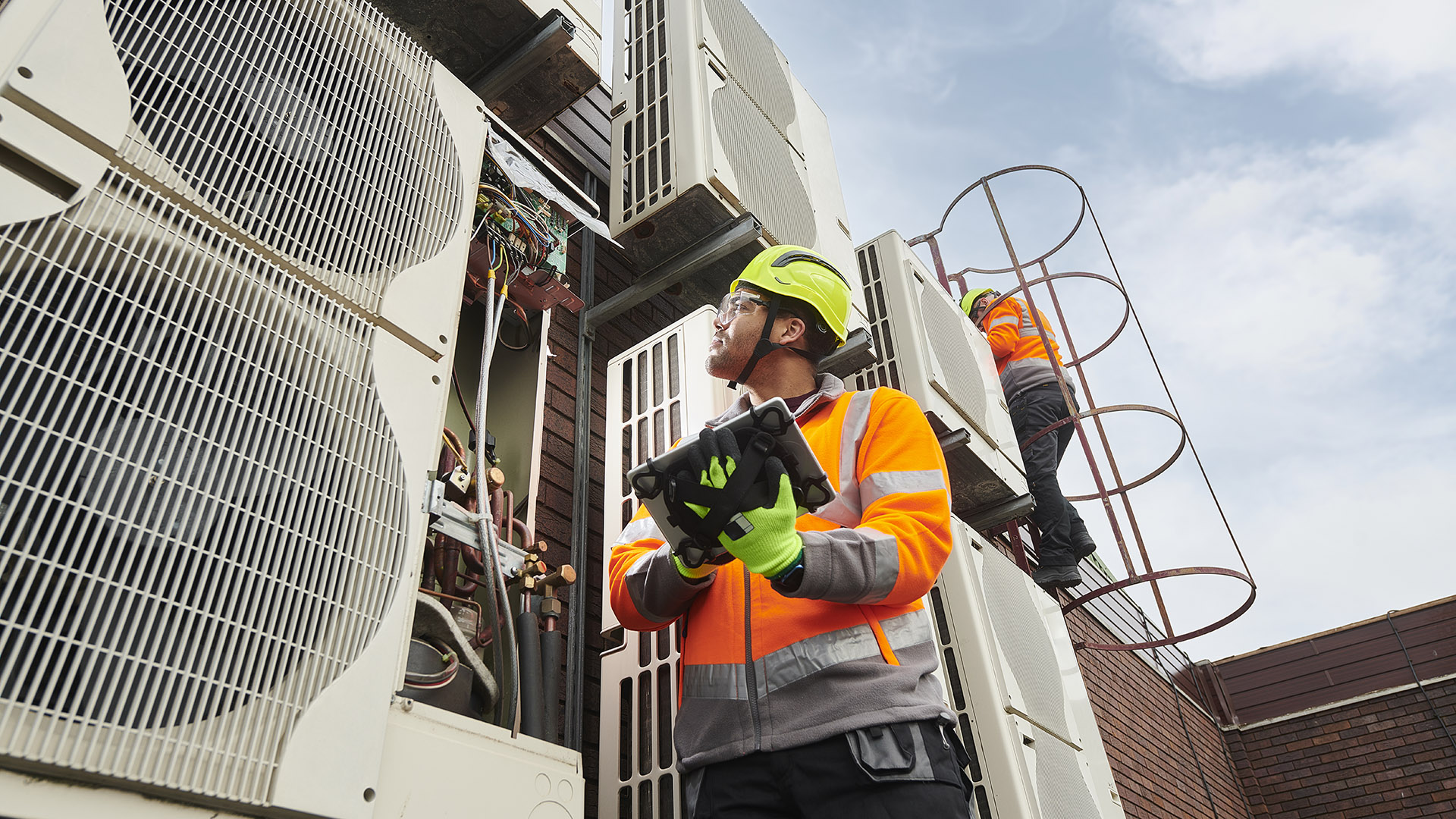 Men in hard hats inspect a building HVAC system.