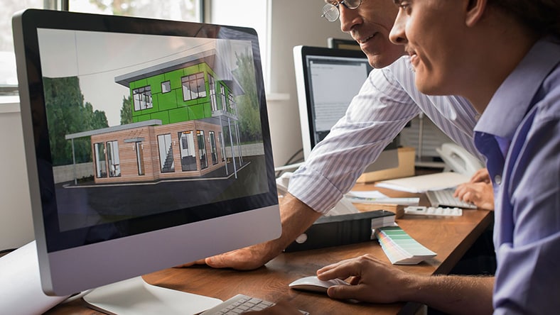 Two men look at a computer monitor displaying a building rendering with energy modeling and simulation.