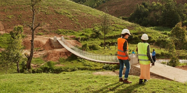 Engineers work on a suspended bridge in rural Rwanda