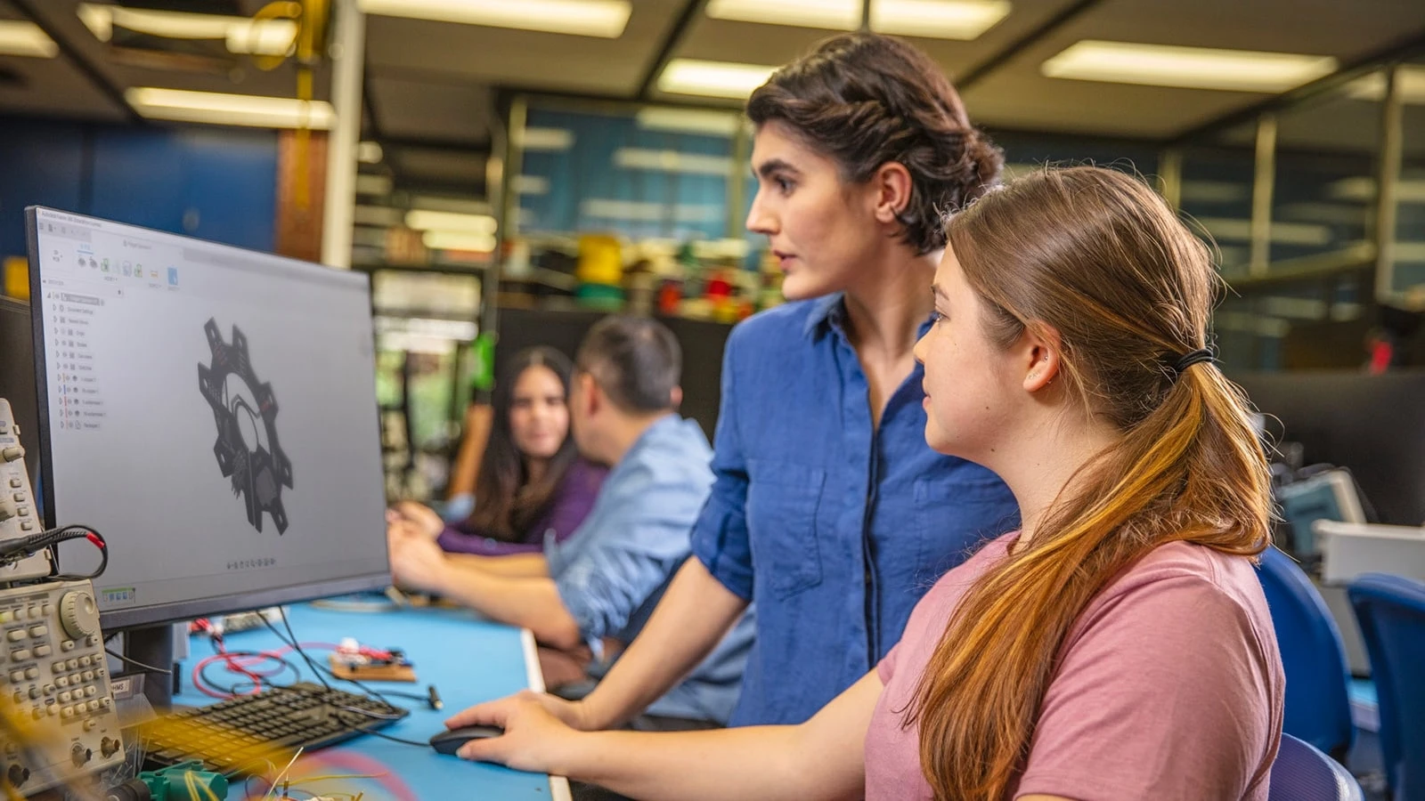 Two women in a workshop look at a computer monitor