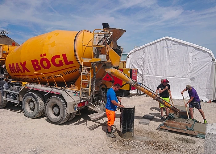 Men work with cement coming out of a Max Bögl cement truck.