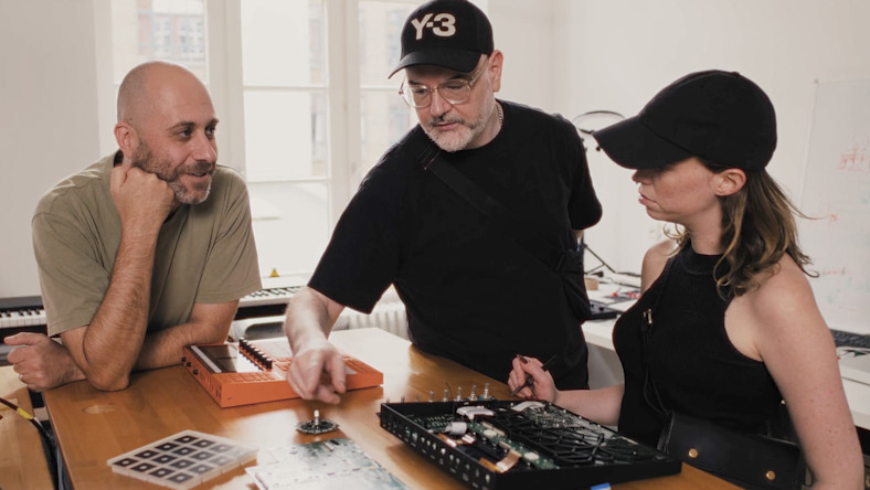 Let there be smarter instruments Three people looking at keyboard parts and discussing them