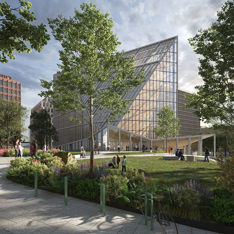Un edificio triangolare con vetrata si erge sopra gli spazi verdi paesaggistici dove le persone si rilassano e si godono l'aria aperta.