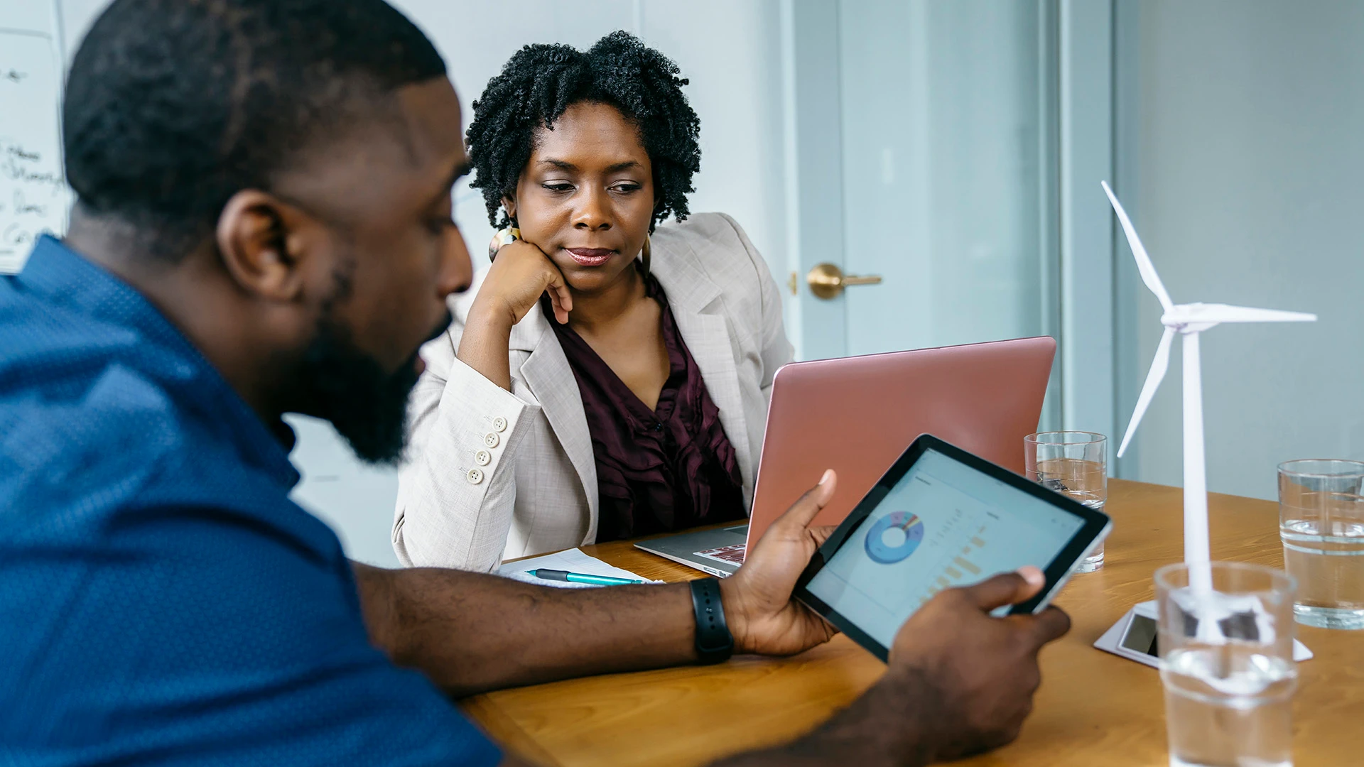 A businessman shows a digital tablet to female colleague.