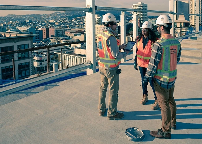 Three people in construction hats on rooftop