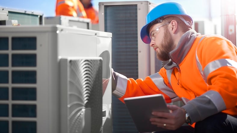 An air conditioning engineer works on units on a rooftop.