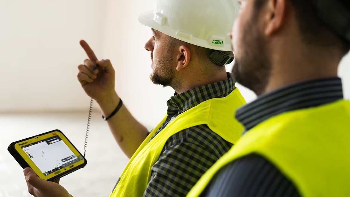 Two construction site workers using a tablet