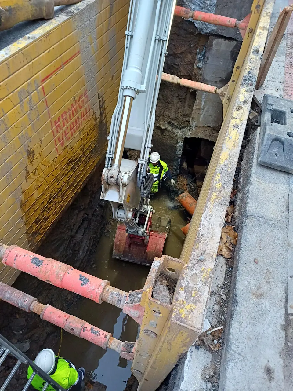 Two workers operate the hose of a sewer-cleaning truck on a Bilbao street. 