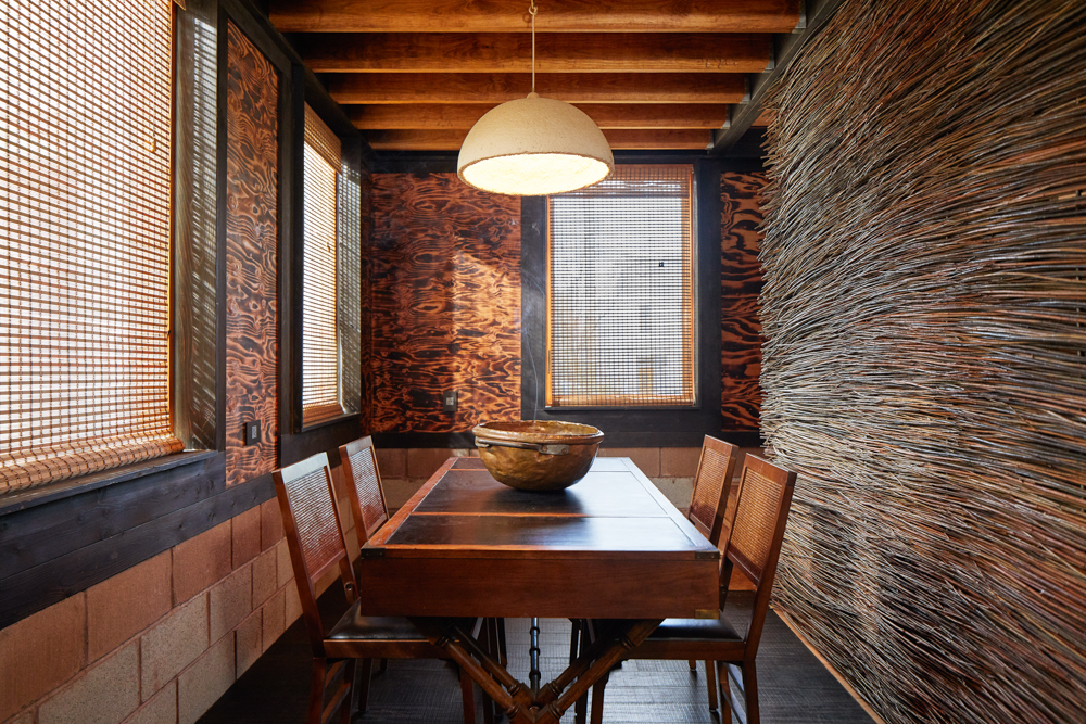 Dining area in Grass House with table and four chairs and willow branches for interior wall