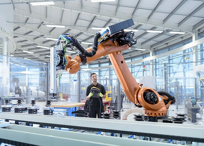a man views a robot in a factory.