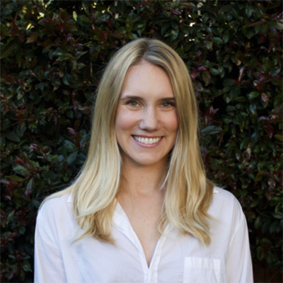 A woman in a white shirt smiles at the camera.