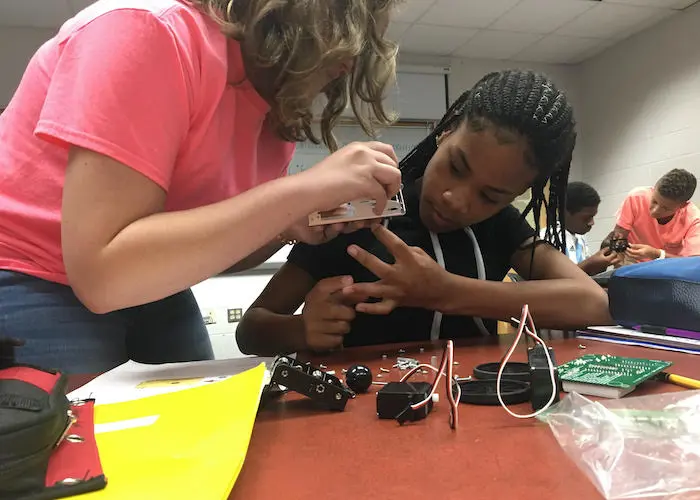 A teacher works with a student on an electronics project