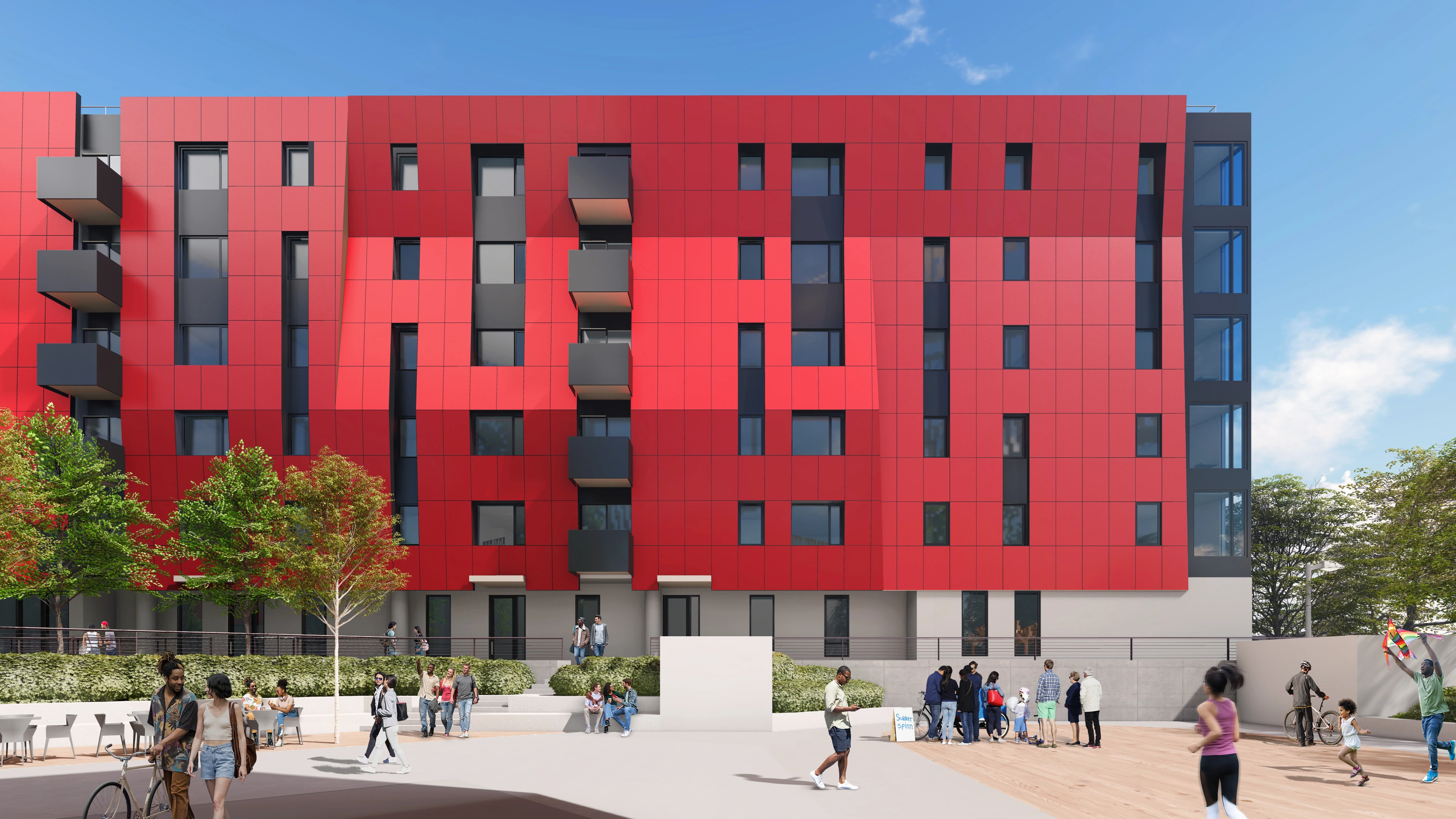 View of open courtyard with concrete benches and area to play and gather in front of multi-story building with red facade