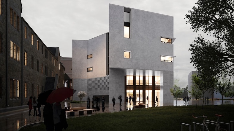 A moody photo shows a modern commercial building, lit from within, on a dark, stormy day.