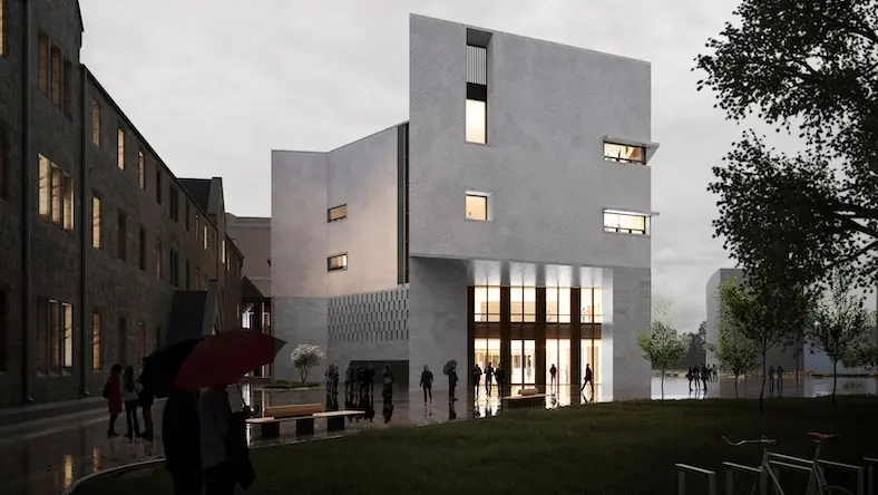 A moody photo shows a modern commercial building, lit from within, on a dark, stormy day.