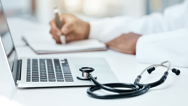 A doctor takes notes at his desk.