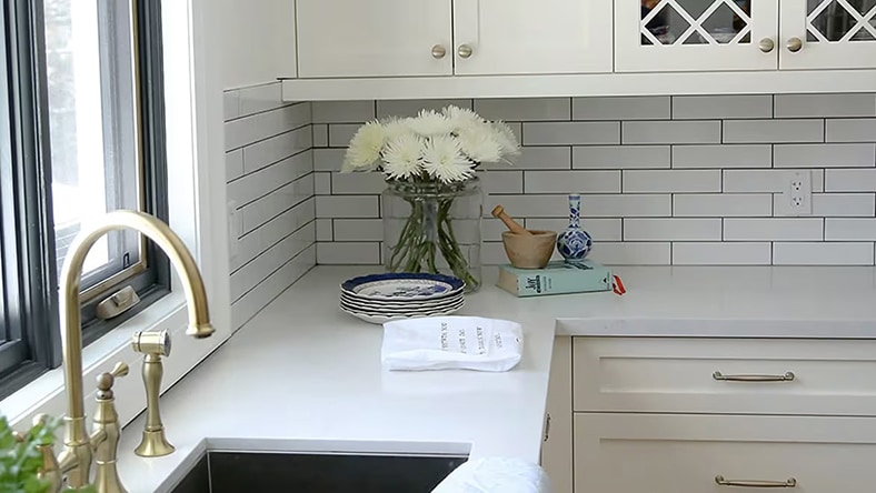 An image shows the sink, counter, and cabinets in a modern white kitchen.