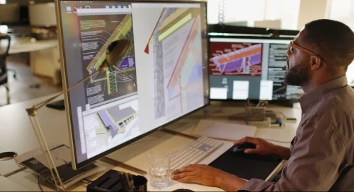 A man consults architecture software on a computer workstation screen.