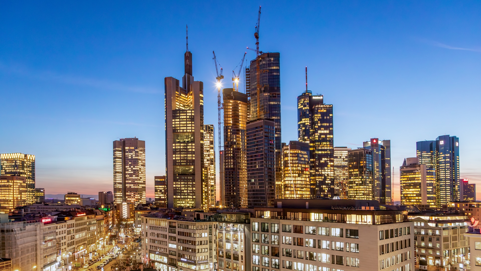 The Frankfurt skyline, shown at dawn, is dotted with construction cranes.
