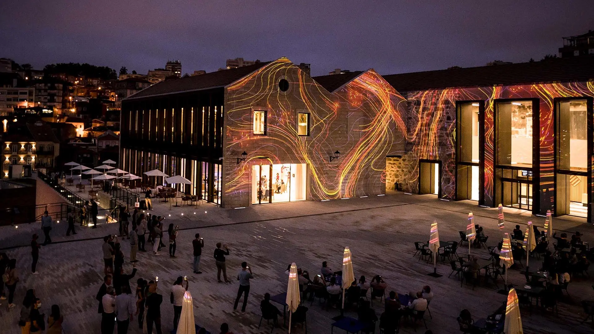 Light projections animate a restored industrial building at night.