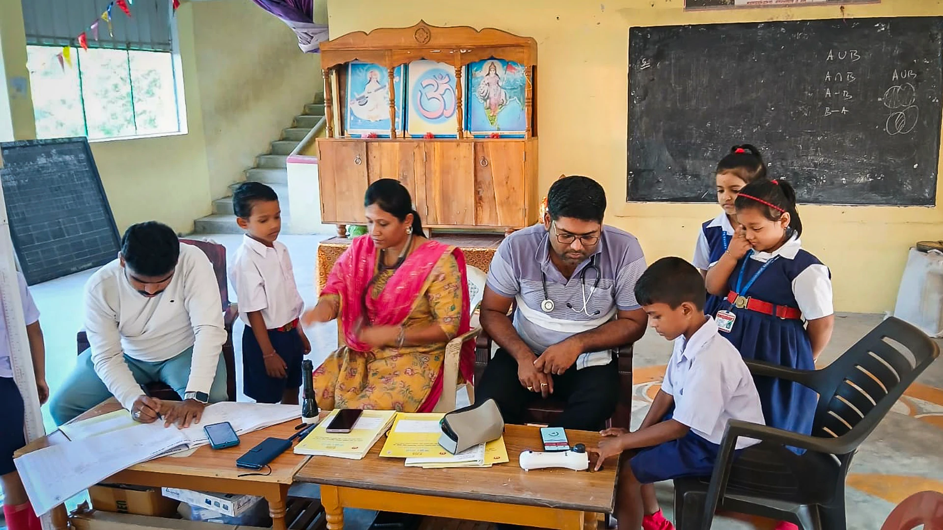A campus health camp in a classroom where two medical staff members are conducting non-invasive health check-ups for students using EzeCheck