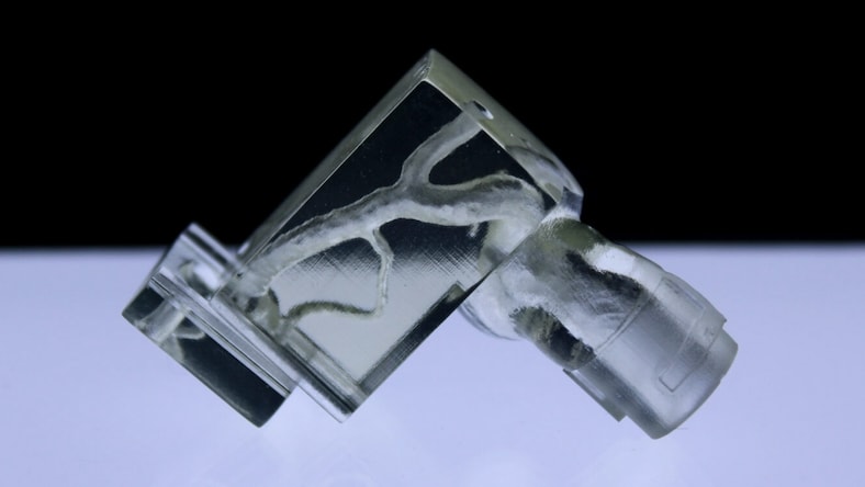 A close-up view of a 3D-printed artery model made with transparent resin.
