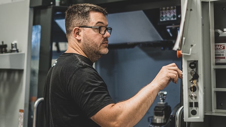 A man works the controls in a machine shop.