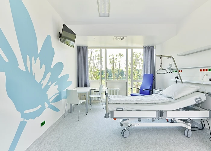 A white hospital room with a blue flower on the wall