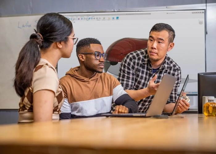 three people collaborating in front of a computer