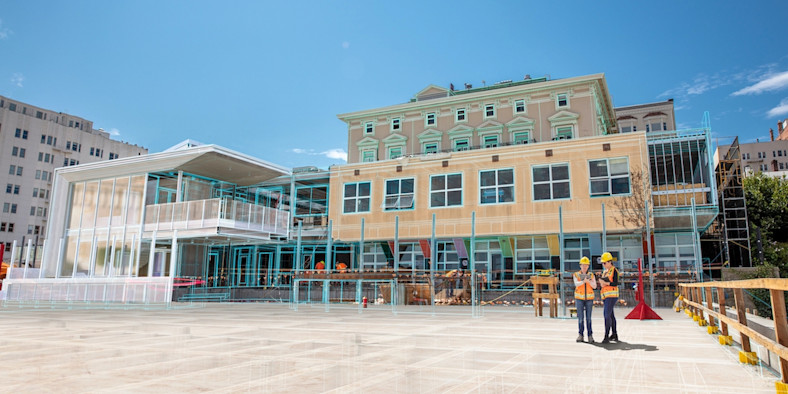 Construction workers stand in front of a building with a digital overlay