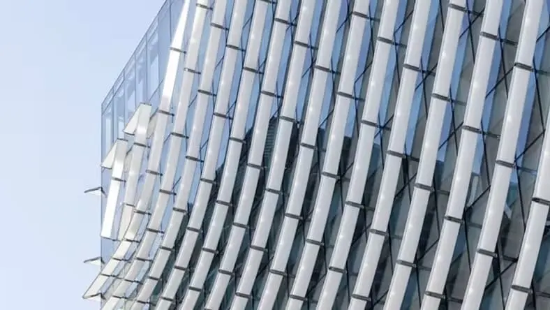 A close-up of a building facade shows undulating waves of aluminum and glass.