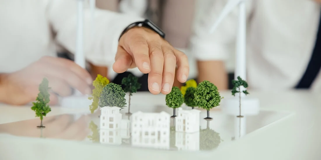 A man's hand hovers over a physical model of a building development