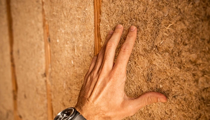 Hand of a white male touches HempWool plant-based insulation