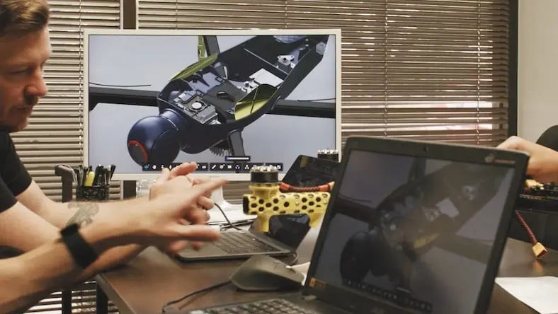 A man designs a machinery part at a computer workstation.