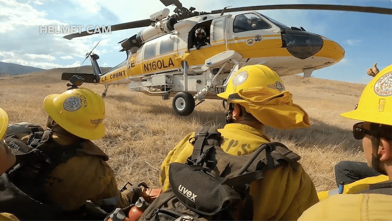 Creative review helmet cam still of firefighters and helicopter in field