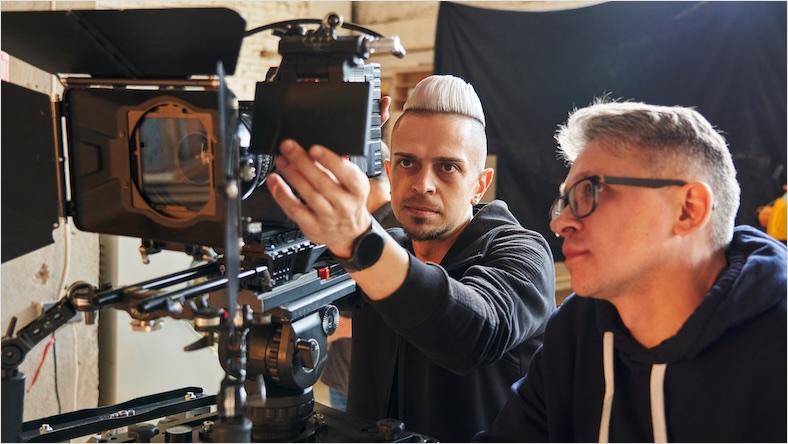 Two men look at the monitor on a professional video camera.