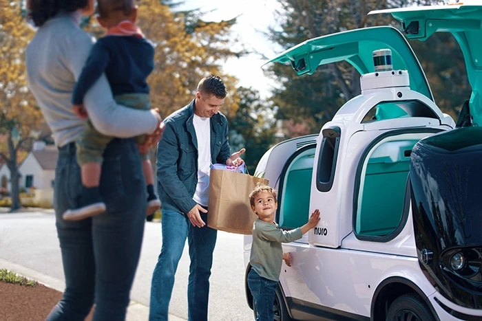 Family stands outside of Nuro autonomous delivery vehicle