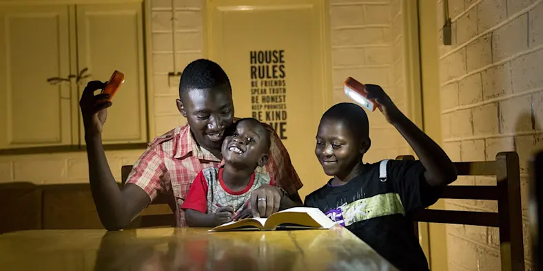 Two happy children and an adult studying by solar light