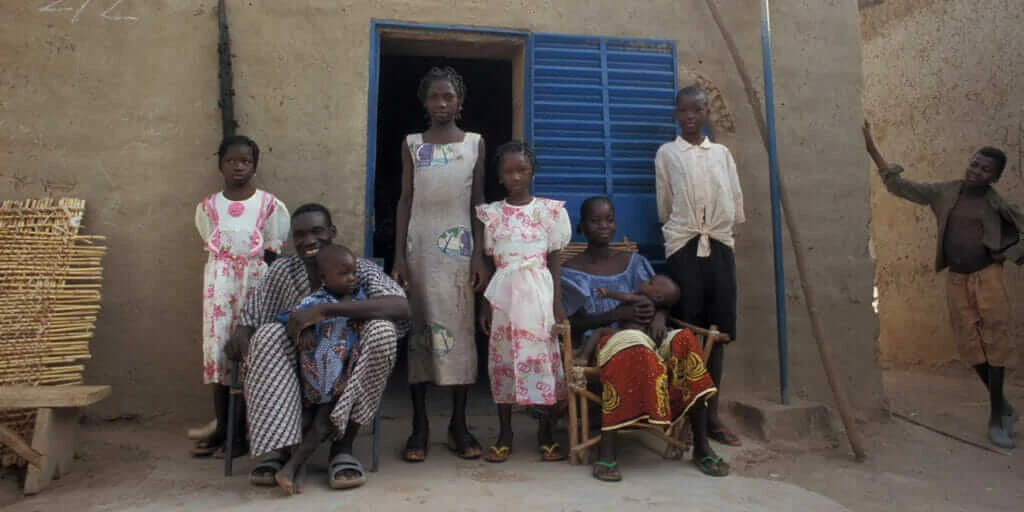 a family in Africa posing in front of their home