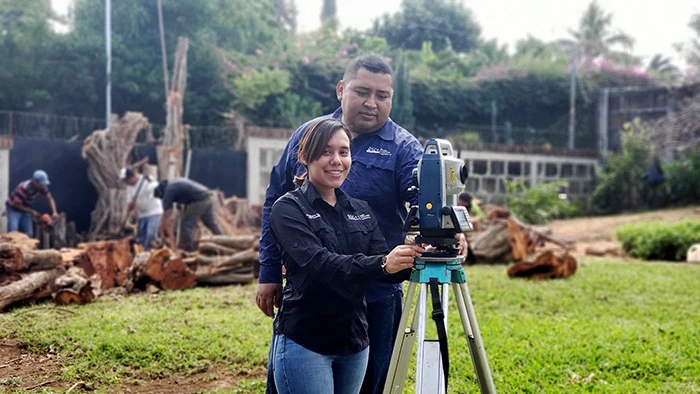 A woman and a man stand with a surveying camera.