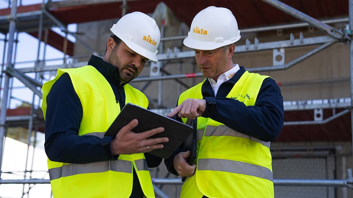 Two employees on a construction site using a tablet